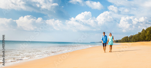 Couple walking on beach. Young happy interracial couple walking on beach smiling holding around each other. Banner