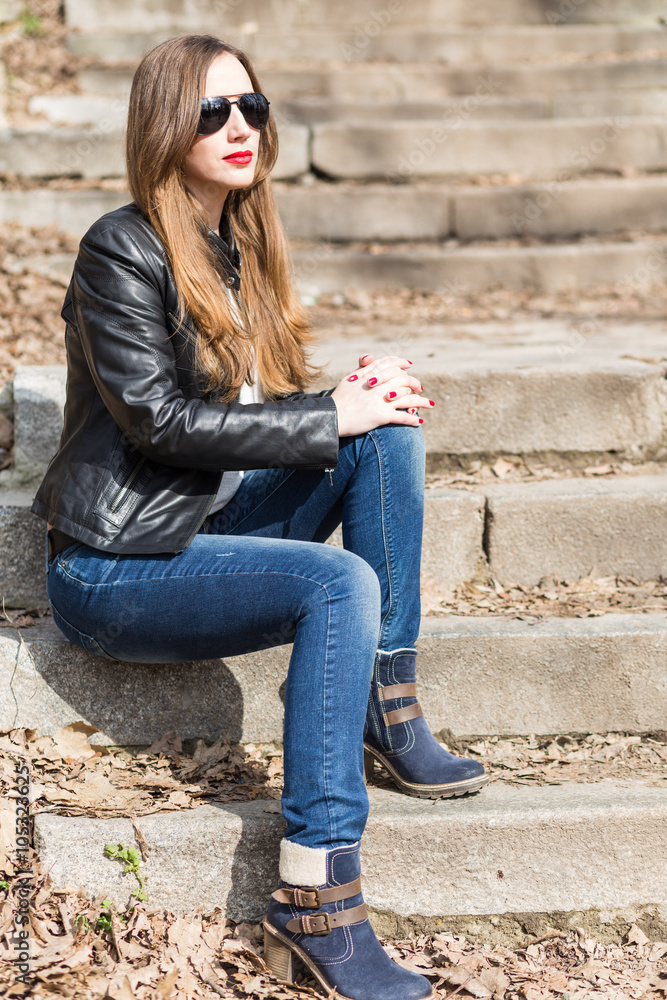 Young woman in leather jacket resting on stairs Young woman in leather jacket resting on stairs