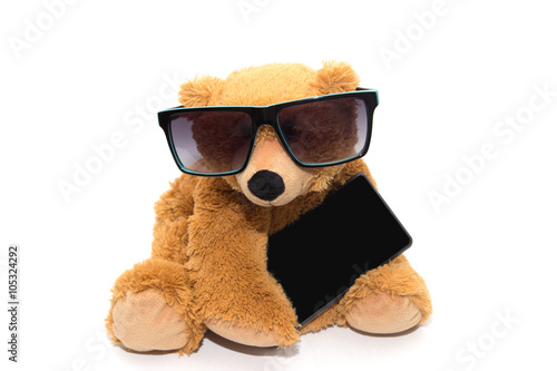 Cool teddy bear in sunglasses with phone isolated