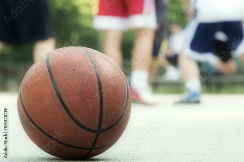 Basketball ball detail with de-focused players.