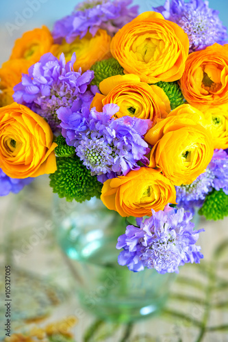Beautiful bouquet of flowers.Yellow ranunculus flowers and scabious close-up in a glass vase on the table.