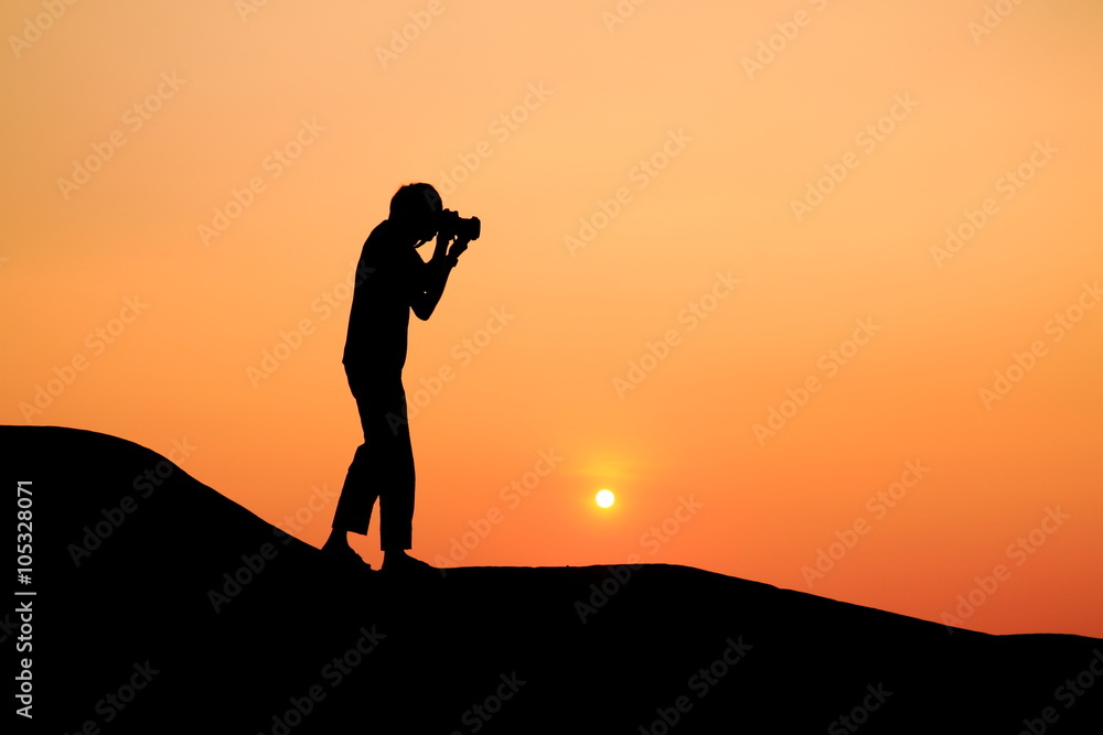 Silhouette picture of a man try to take photograph in sunset