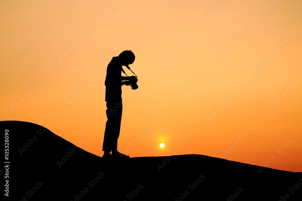Silhouette picture of a man prepare to take photograph in sunset