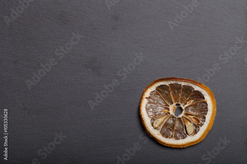 Slices of dried lemon on a black slate cutting board