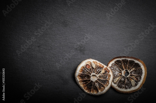 Slices of dried lemon on a black slate cutting board. Toned © strannik_fox