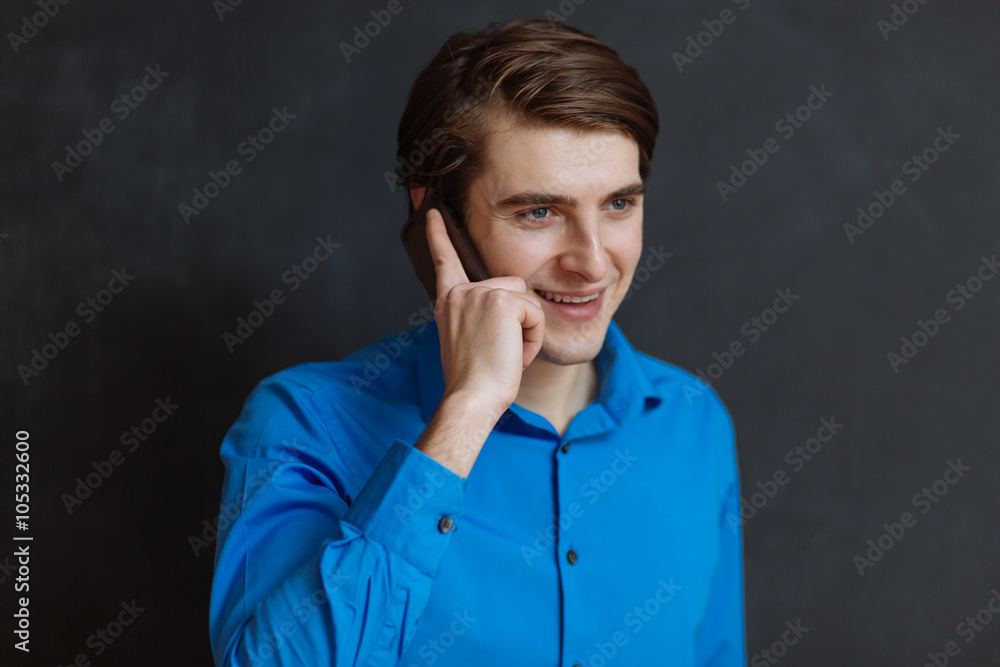 Handsome businessman with mobile phone over black background