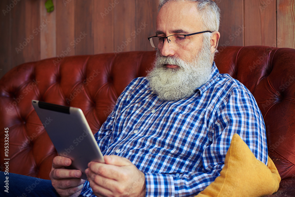 bearded man sitting on sofa and reading news bearded man sitting on sofa and reading news