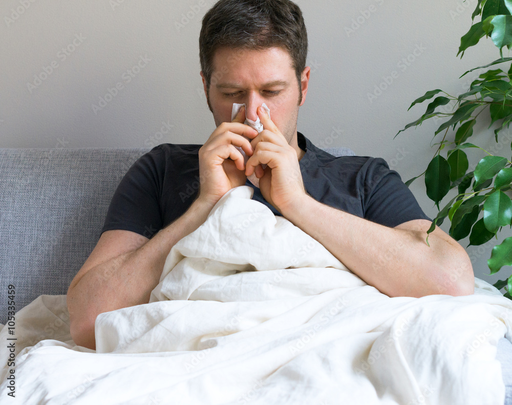 Sick Man Blowing His Nose While Lying On Bed At Home Stock Photo Adobe Stock