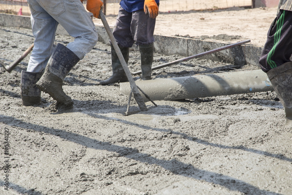 Group of construction workers spreading freshly poured concrete