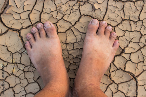 Barefoot standing on dry and cracked ground background and textu