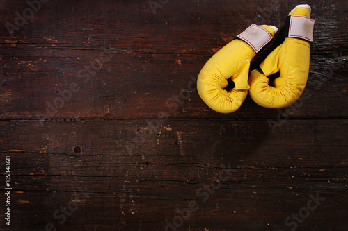 Yellow boxing gloves on a rusty wooden floor