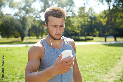 young man with earphones and smartphone at park