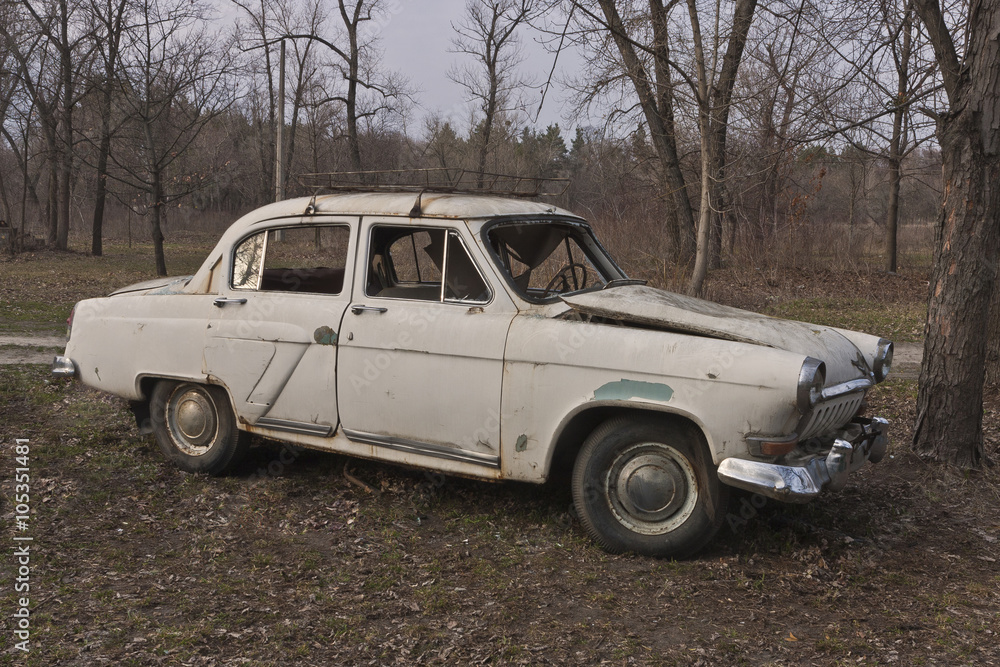 An old broken soviet car in thin forest environment