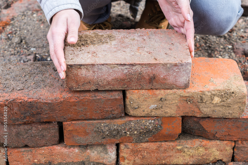 Person schichtet Ziegelsteine übereinander StockFoto Adobe Stock