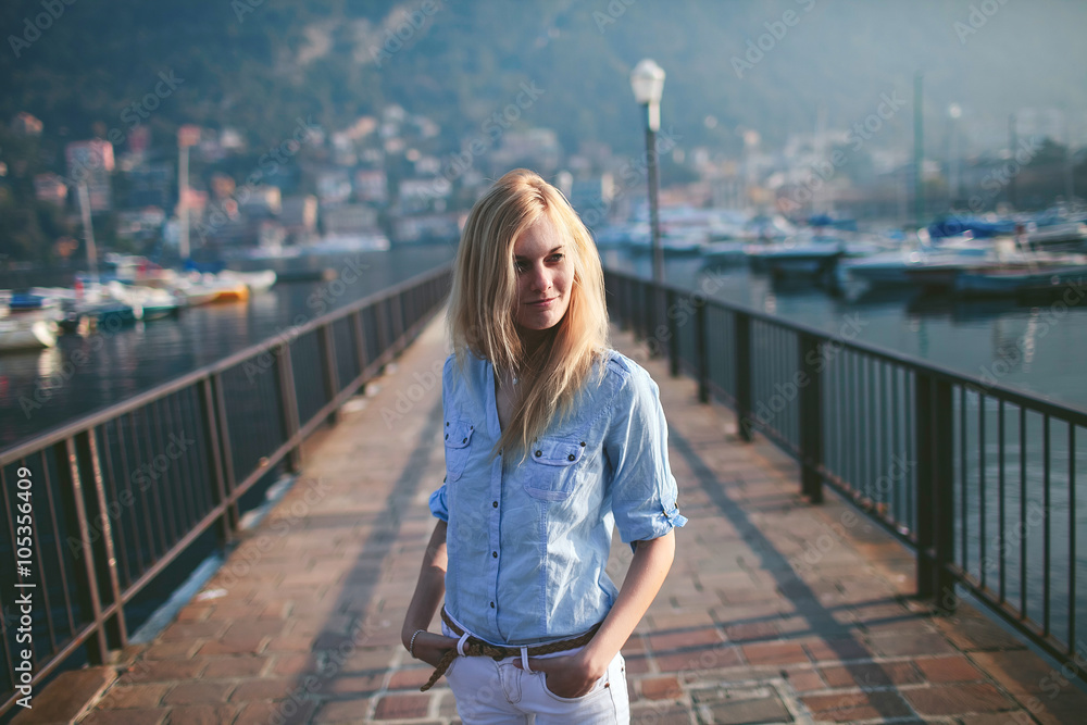 blonde girl walks on the pier of a mountain lake como italy