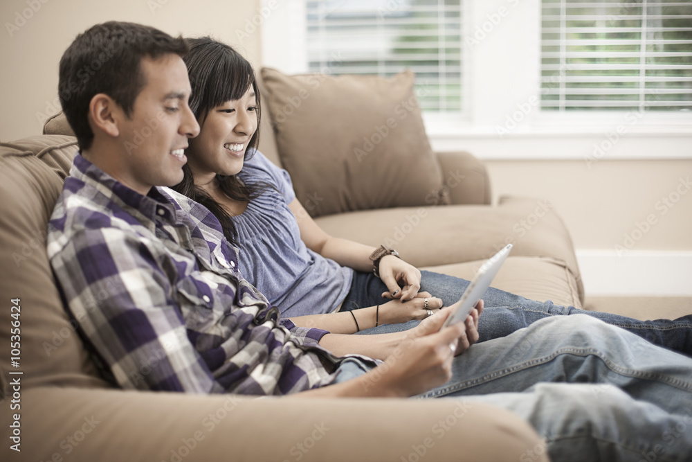 A couple sitting on a sofa, using a digital tablet, A couple sitting on a sofa, using a digital tablet,