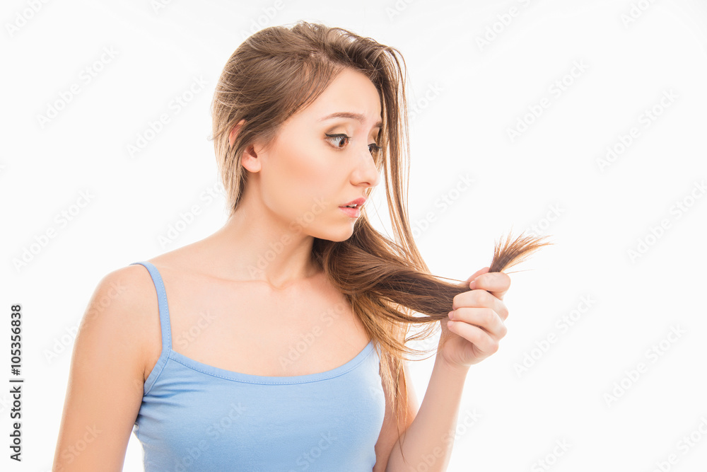 Young woman looking at her damaged split ends Young woman looking at her damaged split ends