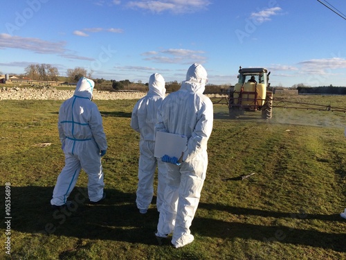 agricultores con trajes de proteccion sulfatando el campo