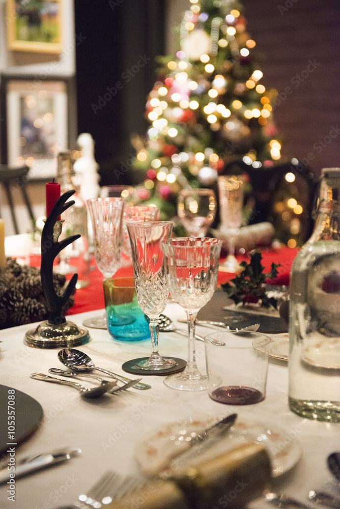 A table laid for a Christmas meal, with silver and crystal glasses and a Christmas tree in the background, A table laid for a Christmas meal, with silver and crystal glasses and a Christmas tree in the background,