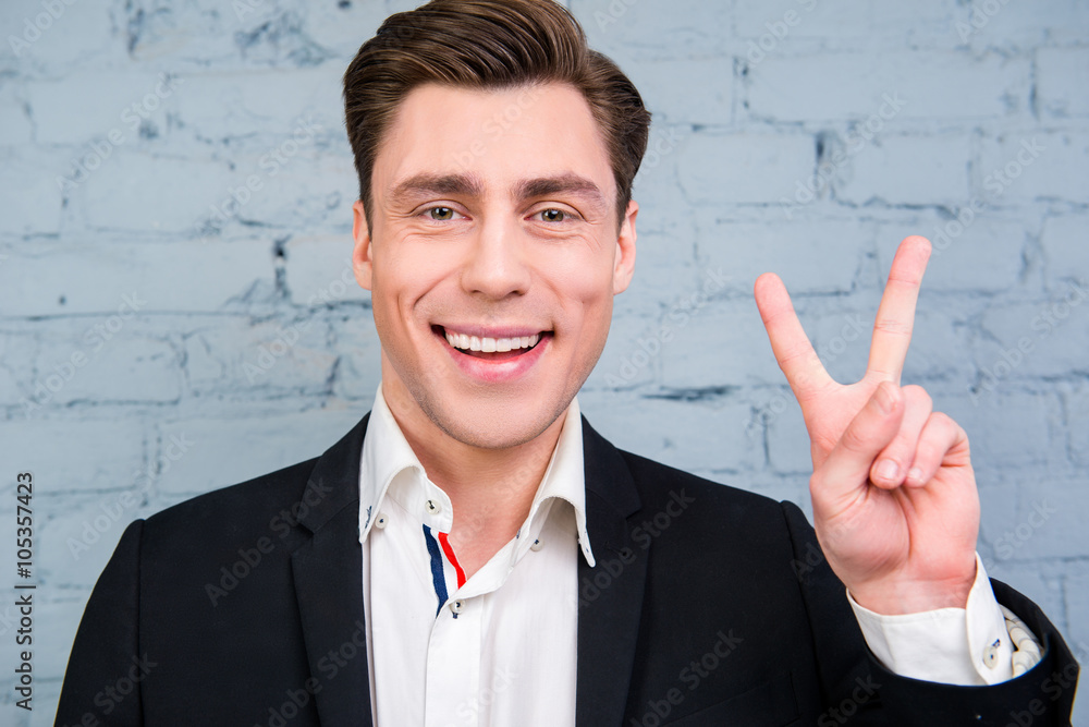 Portrait of cheerful young businessman gesturing with two finger