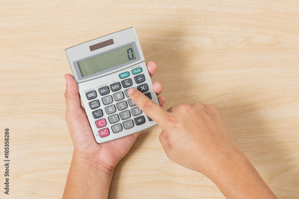 Hand hold and press Calculator on Wood Background Hand hold and press Calculator on Wood Background