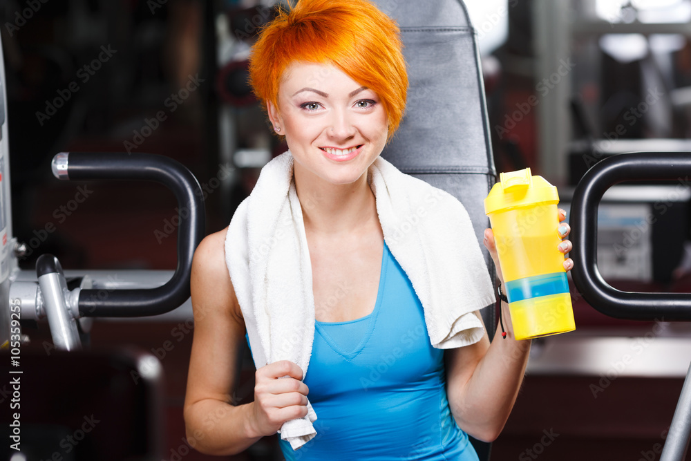 Obraz premium Pretty fit girl with red short hair in gym