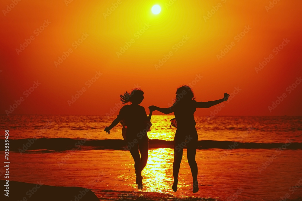 Fototapeta premium Happy Girls Jumping in Sea Sunset. Silhouette. Thailand.