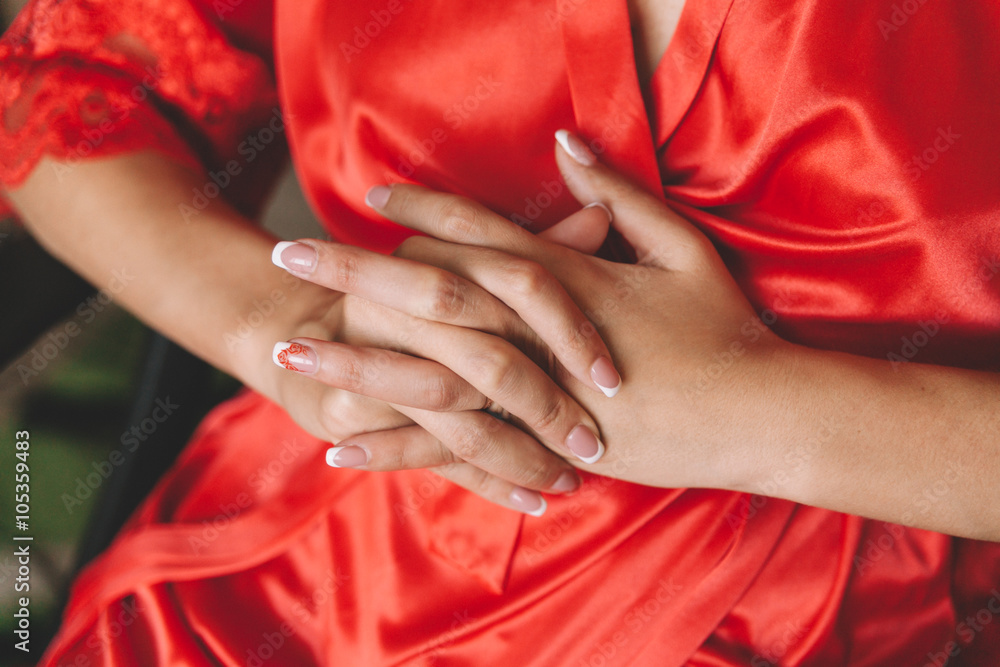 Hands of a woman in a red silk robe with a nice manicure