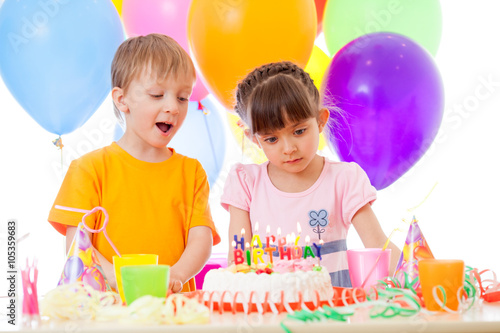 Happy children look at birthday cake