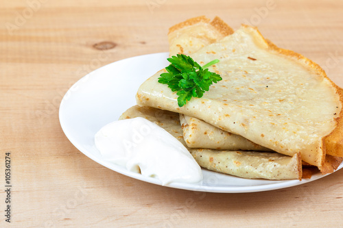 Pancakes with sour cream in a bowl.