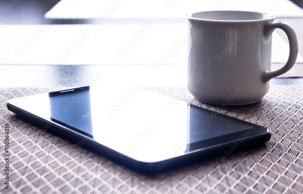 Coffee cup and tablet pc on kitchen table Coffee cup and tablet pc on kitchen table