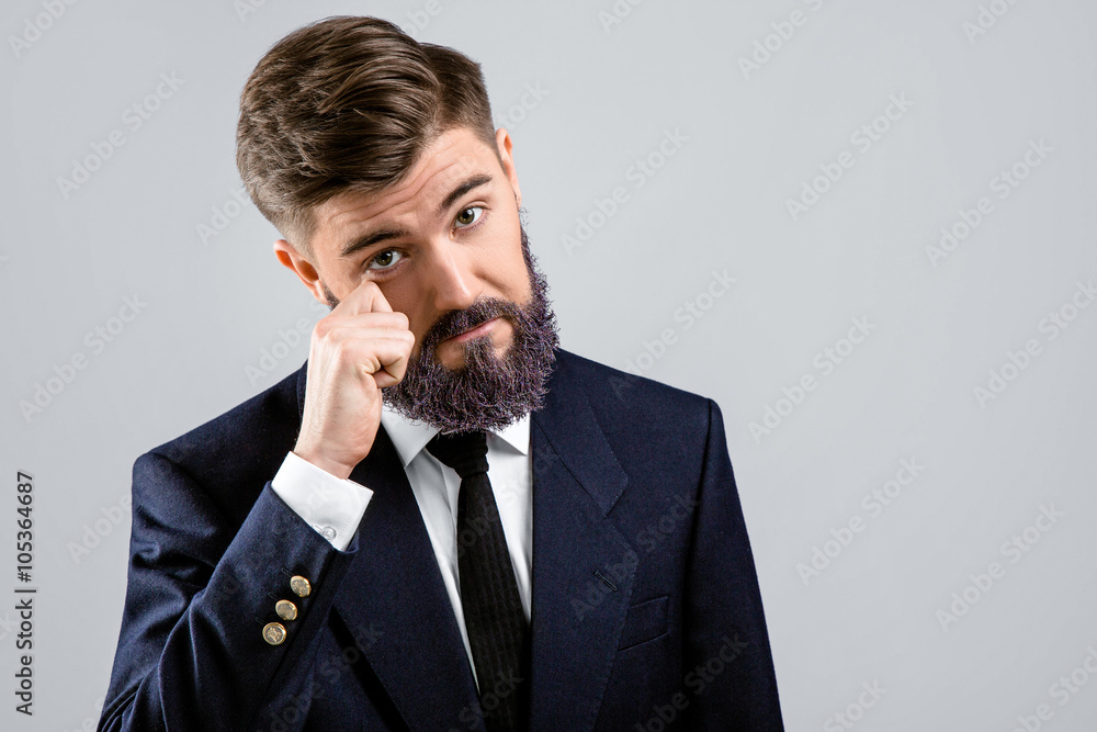 Young upset businessman standing with hand near his face Young upset businessman standing with hand near his face
