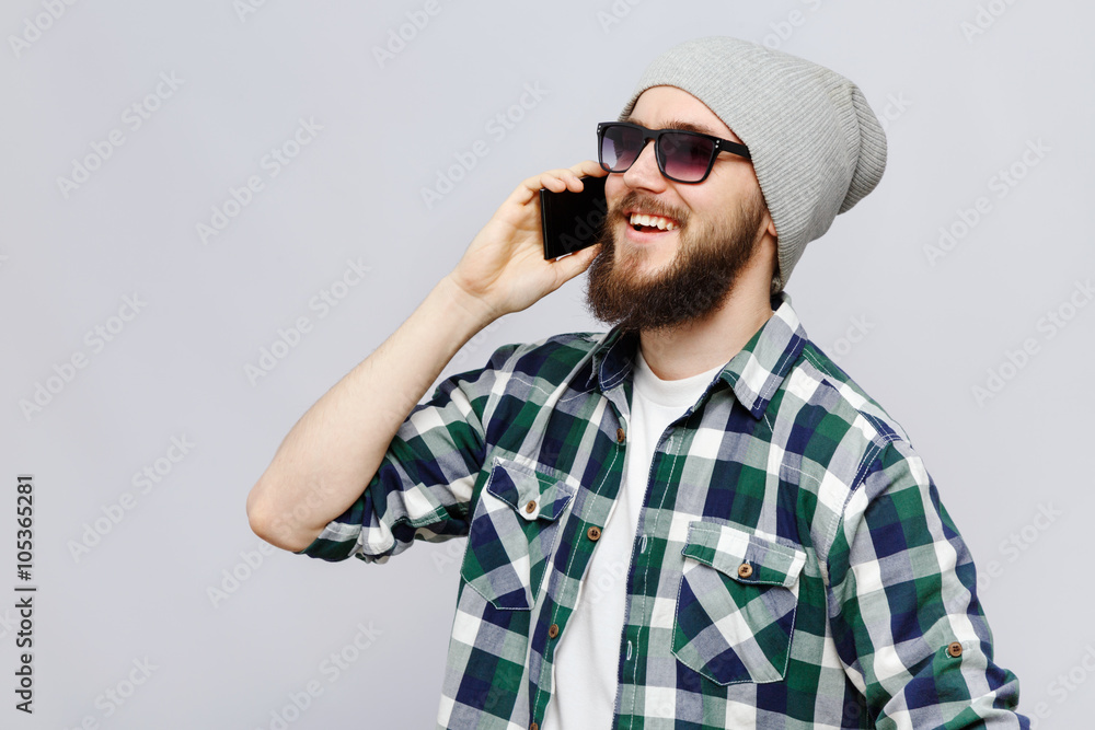 Happy young bearded man talking on his smart phone Happy young bearded man talking on his smart phone