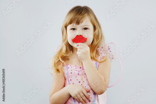 Cheerful little girl posing with red paper lips