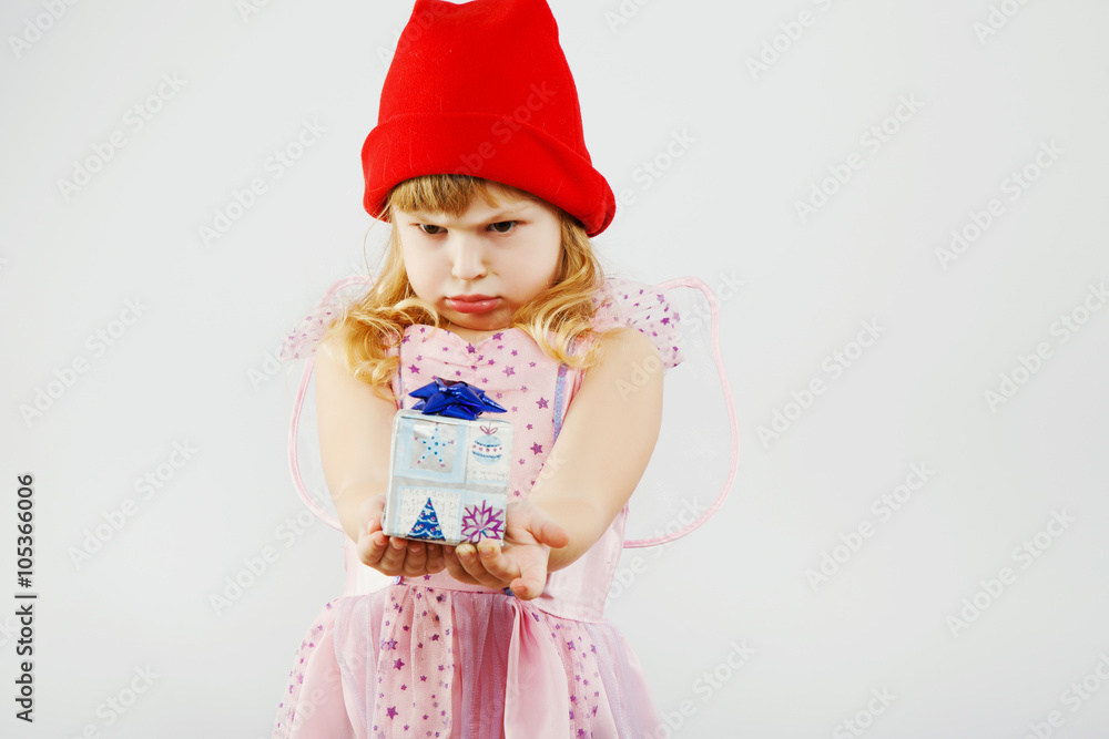 Dissatisfied little girl looking on little present in her hands Dissatisfied little girl looking on little present in her hands