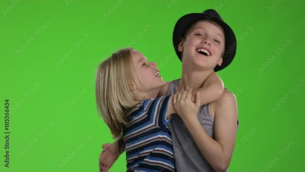 Two childs hugging each other and having fun in front of greenscreen Two childs hugging each other and having fun in front of greenscreen