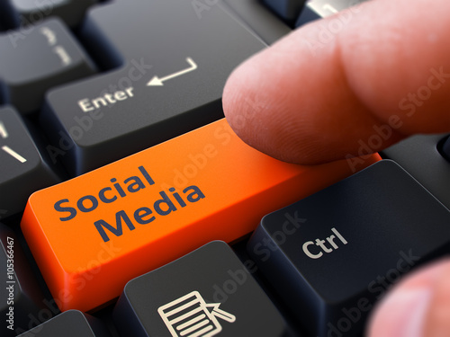 Social Media Button. Male Finger Clicks on Orange Button on Black Keyboard. Closeup View. Blurred Background. 3D Render. photo