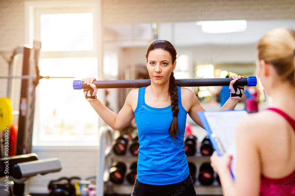 Woman exercising in gym, personal trainer, plan on clipboard Woman exercising in gym, personal trainer, plan on clipboard