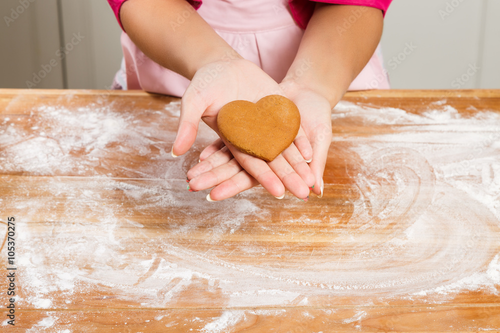 Young woman holding gingerbread in her hand in the kitchen Young woman holding gingerbread in her hand in the kitchen