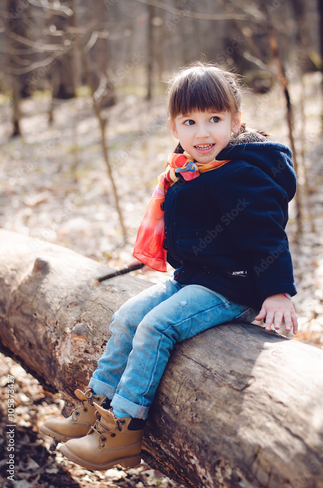 little girl sitting on a log in the spring forest little girl sitting on a log in the spring forest