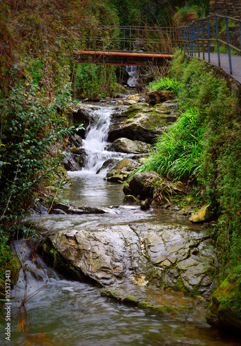 mountain stream waterfall with stones and bridge