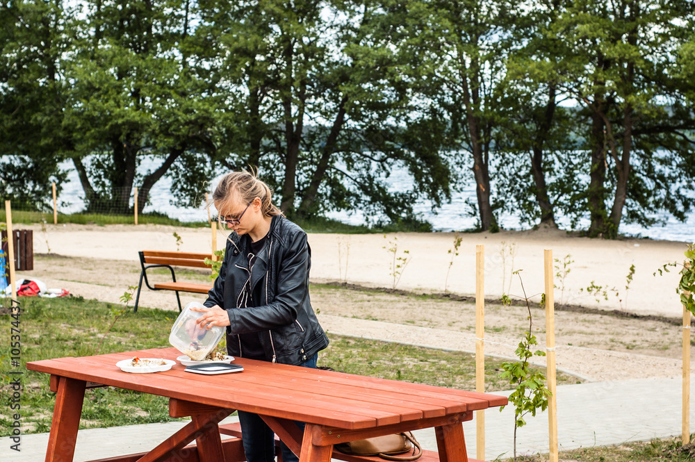 Fototapeta premium Woman eating outdoors by the lake, summer vacation and relaxation time
