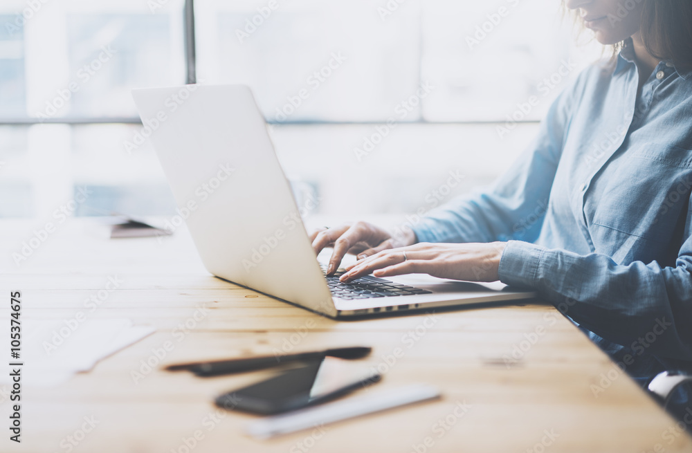 University work process concept. Student girl working new project with generic design laptop. Smartphone wooden table, texting message. Blurred background, film effect. Horizontal University work process concept. Student girl working new project with generic design laptop. Smartphone wooden table, texting message. Blurred background, film effect. Horizontal