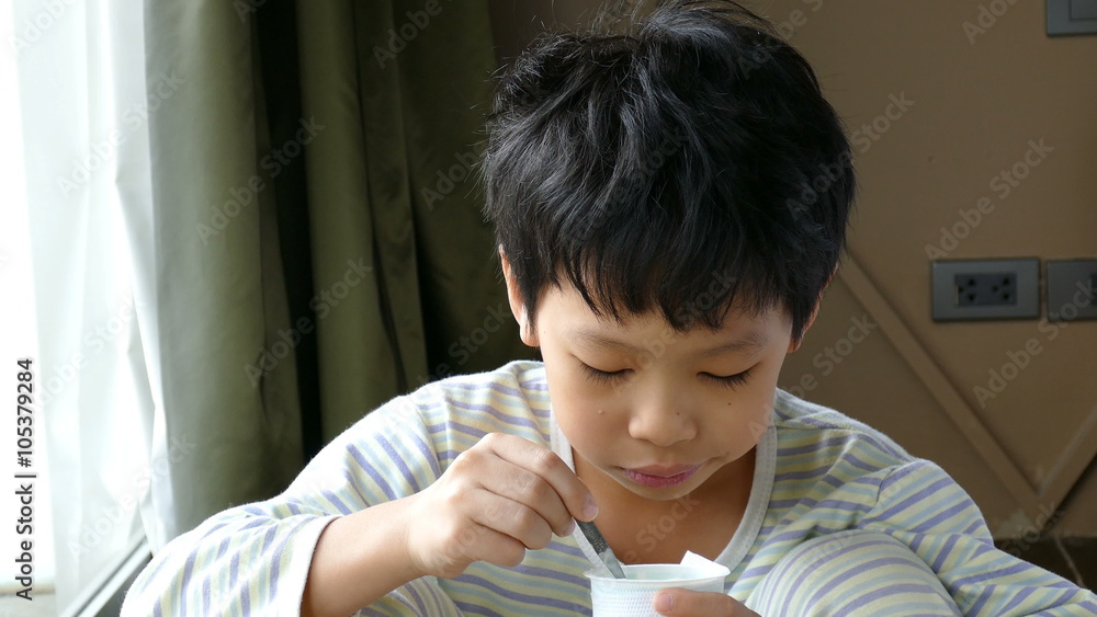 Young Asian boy eating yogurt in at home