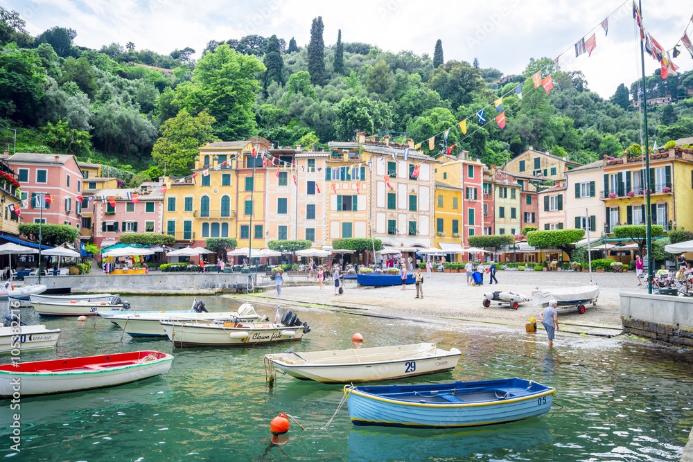 Pier and boats on bockground of colorful houses in bay of Portofino, Italy.