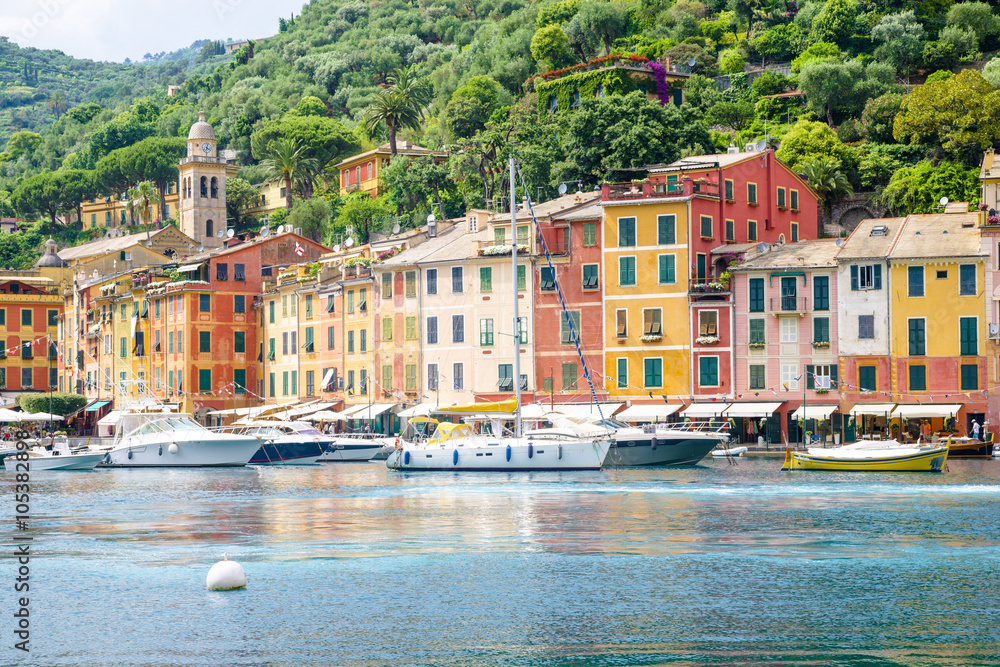 Pier and boats on bockground of colorful houses in bay of Portofino, Italy.