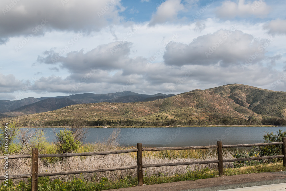 At Otay Lakes County Park in Chula Vista, California, a scenic view of a mountain range, the lake and a fence line.  