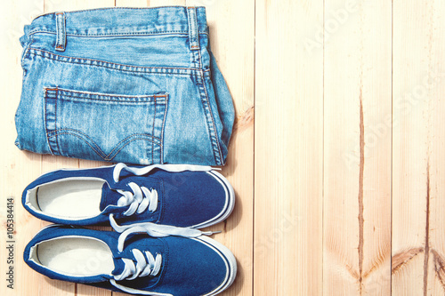 Youth blue sneakers and jeans on wooden background with copy spase
