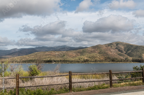 At Otay Lakes County Park in Chula Vista, California, a scenic view of a mountain range, the lake and a fence line. 