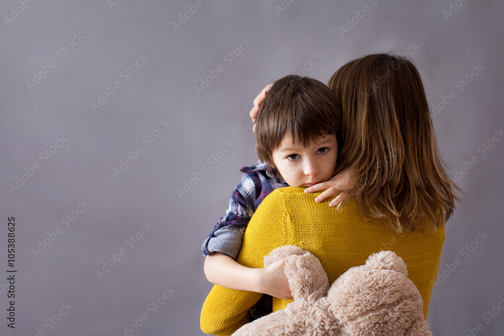 Sad little child, boy, hugging his mother at home